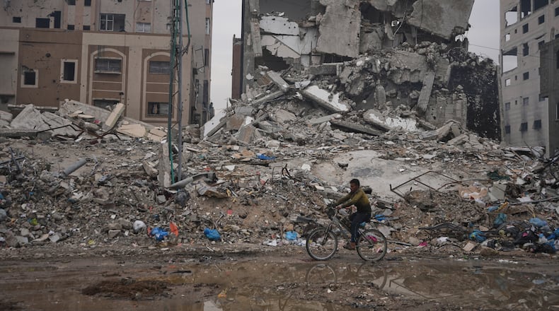 A Palestinian man rides a bicycle past destroyed buildings in Gaza City Sunday, Jan. 4, 2026. (AP Photo/Jehad Alshrafi)