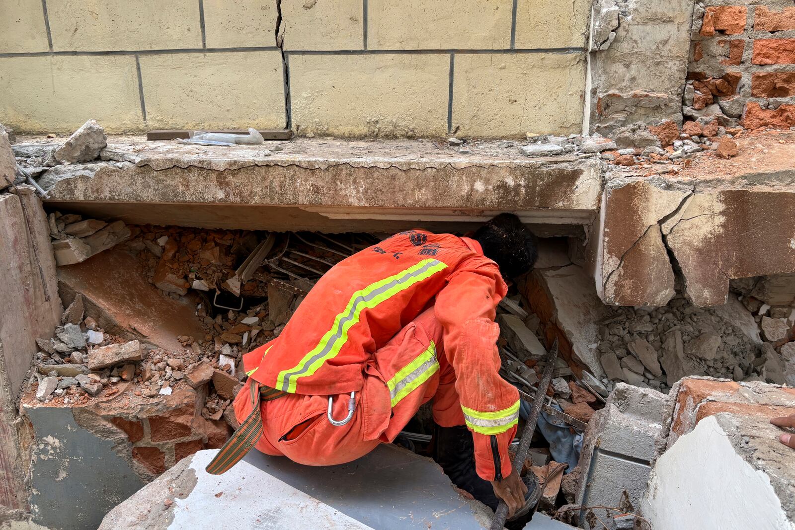 A firefighter recovers the belongings of victims from damaged buildings that house Governments' servants in Naypyitaw, Myanmar, Monday, April 28, 2025, one month after the earthquake. (AP Photo/Aung Shine Oo)