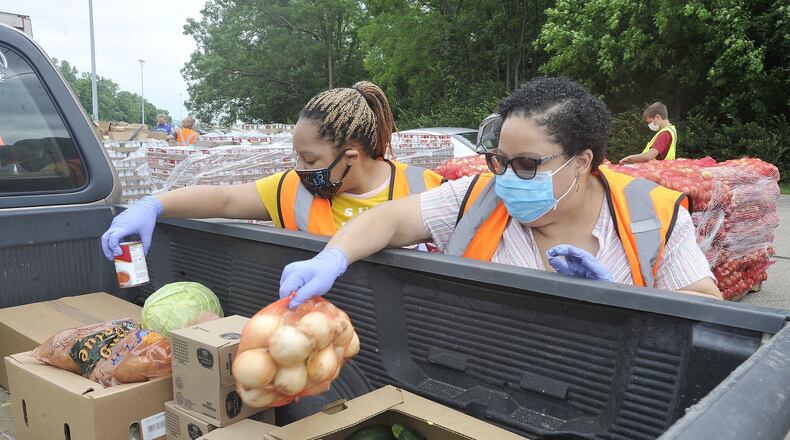 Volunteers help load food into vehicles at the Greene County food distribution at the Wright State Nutter Center Wednesday. MARSHALL GORBYSTAFF