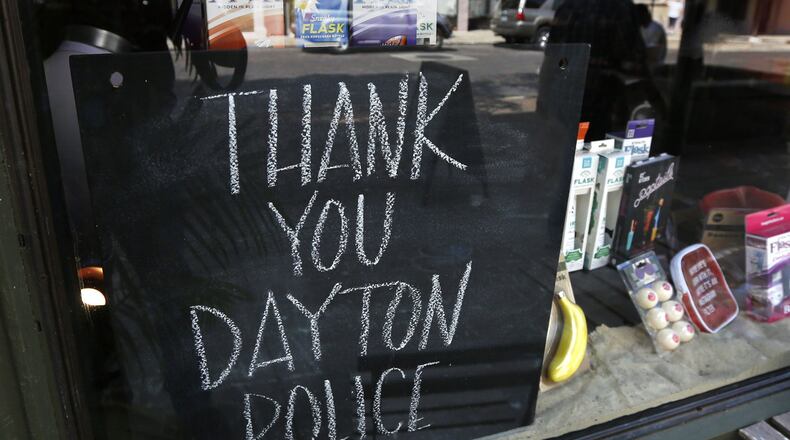 Signs supporting the Dayton Police Department can be found throughout the Oregon District, including this chalkboard sign at Heart Mercantile. TY GREENLEES / STAFF
