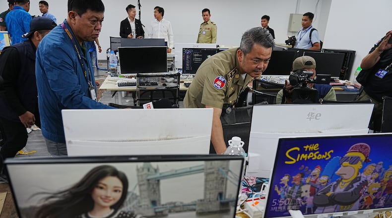Bun Sosekha, Deputy Commissioner in charge of Security Unit, Phnom Penh Municipal Police, checks equipment confiscated in a raid by Cambodian police at a scam center in Phnom Penh, Cambodia, Wednesday, March 11, 2026. (AP Photo/Heng Sinith)