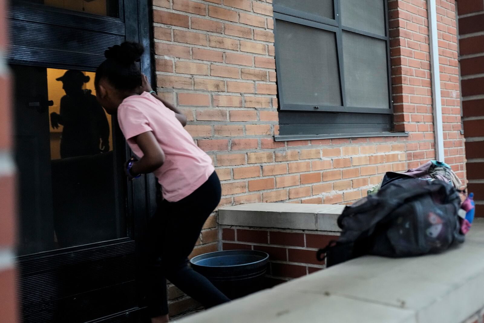 Nova Brown, 5, looks through the front door at her mother, Millicent Brown, from outside their home at a public housing complex on Wednesday, April 2, 2025, in Houston. (AP Photo/Ashley Landis)