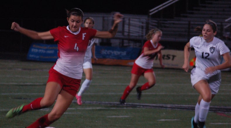 Fairfield’s Lauren Piatt (4) moves the ball up the field as Lakota East’s Ashley Whitehead chases Tuesday night at East. CONTRIBUTED PHOTO BY JOHN CUMMINGS