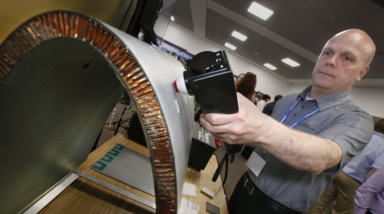 Material engineer Bryan Foos demonstrates a terahertz probe that measures the thickness of coatings of Air Force aircraft. This probe can verify the thickness of paint and coatings for quality control and is expected to be integrated into laser paint removal systems to make the process more accurate. The terahartz probe was part of the AFRL Inspire Tech Expo at the Dayton Convention Center on Thursday. TY GREENLEES / STAFF