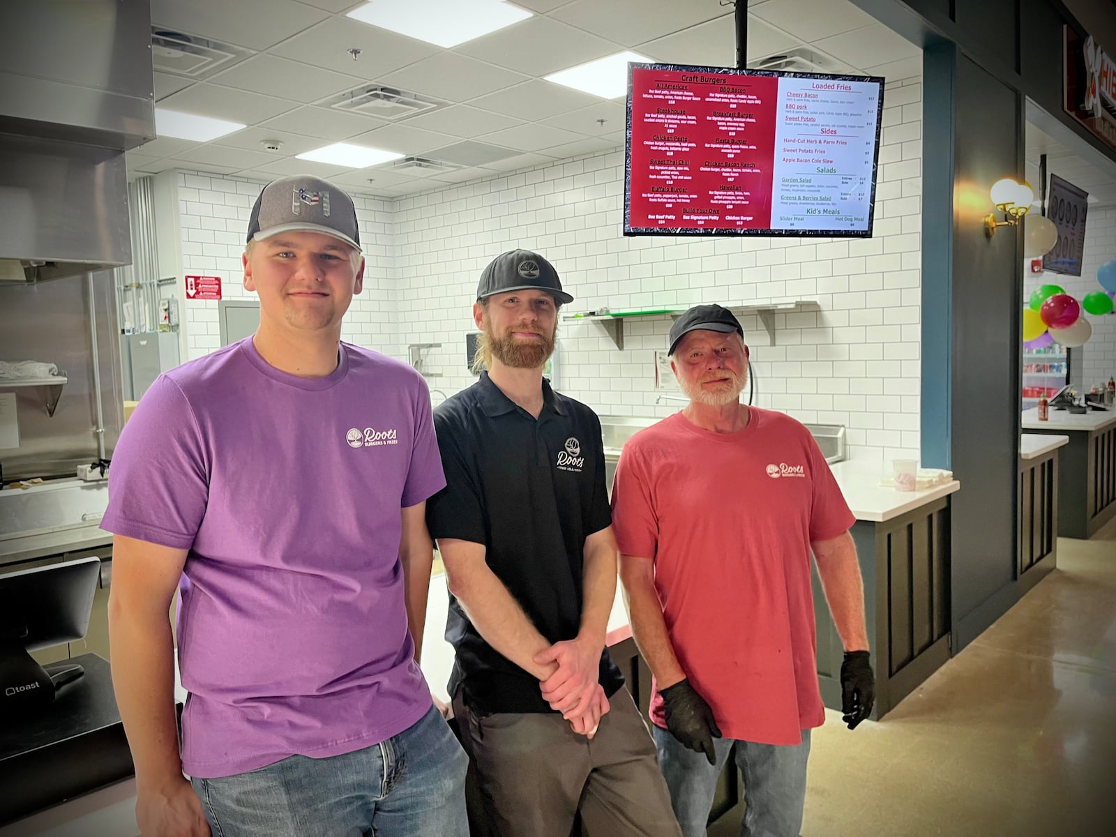 Roots Burgers & Fries is one of six vendors inside The Social at Piqua Center. Pictured is Keegan Livingston and two of his family's employees. NATALIE JONES/STAFF