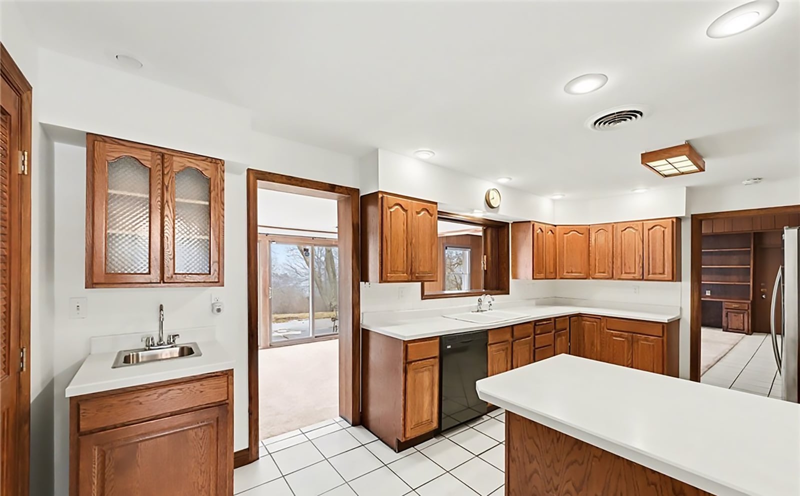 The kitchen has tile flooring, wood cabinets, solid surface countertops and a tile backsplash. There is a double sink and bar sink. CONTRIBUTED