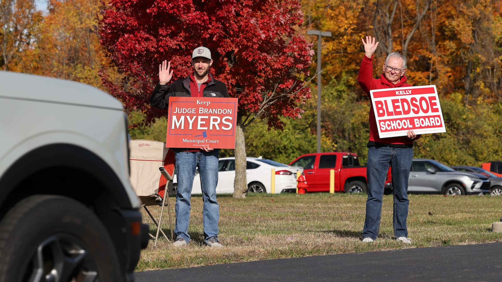 Montgomery County Municipal Court Judge Brandon Myers (left) and Huber Heights City Schools Board Member Kelly Bledsoe wave to cars driving into a polling place at New Season Ministry on Tuesday, Nov. 4, 2025 in Huber Heights. Both said the turnout is somewhat more than they expected. Bledsoe said it had been a "steady stream," all day. He was out when polls opened and said he initially planned to leave around 8 a.m., but he still remained shortly before 11 a.m. due to the consistent arrival of voters. BRYANT BILLING/STAFF
