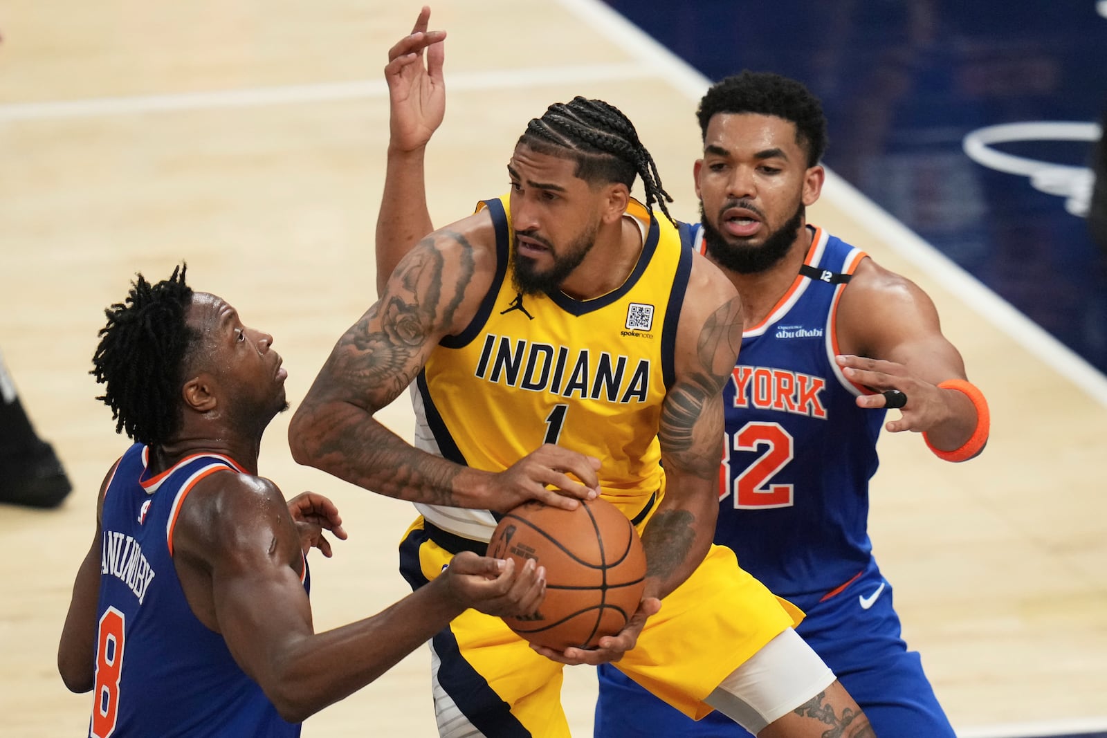 Indiana Pacers forward Obi Toppin (1) looks to pass the ball between New York Knicks forward OG Anunoby, left, and center Karl-Anthony Towns during the second half of Game 3 of the Eastern Conference finals of the NBA basketball playoffs Sunday, May 25, 2025, in Indianapolis. (AP Photo/Jeff Roberson)