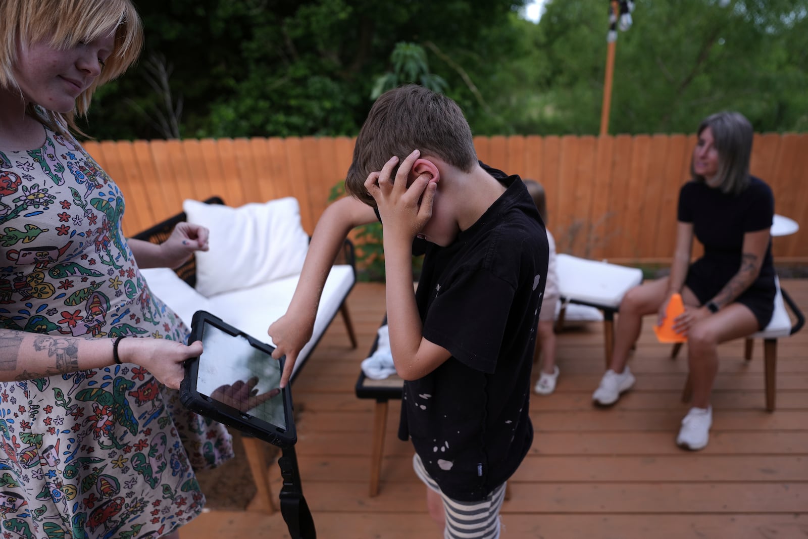 Charlie Lamb, who is diagnosed with autism and is non-verbal, uses an AAC device to communicate with a caregiver, Monday, May 12, 2025, in Austin, Texas. (AP Photo/Eric Gay)