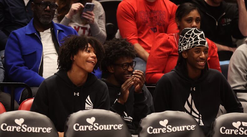 Three recruits from Spire Academy (left to right: Jackson Williams, Jayon Alexander and Collin Ross) watch from behind the bench as Dayton plays New Mexico State on Wednesday, Nov. 20, 2024, at UD Arena. David Jablonski/Staff