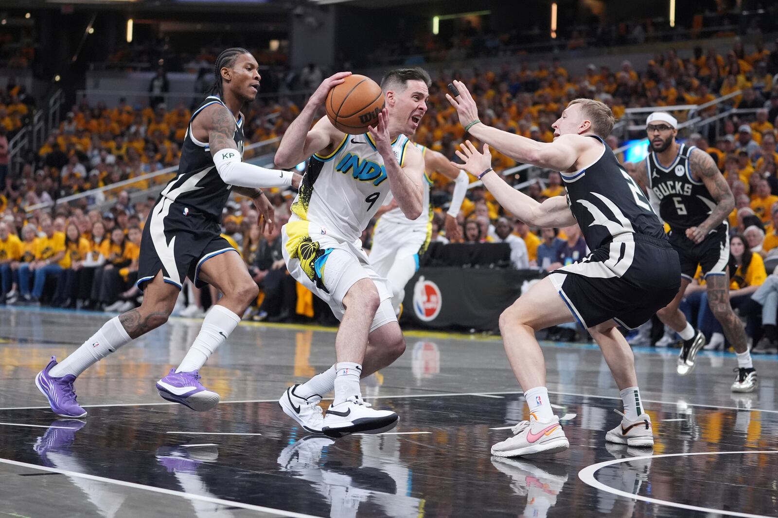 Indiana Pacers' T.J. McConnell (9) heads to the basket as Milwaukee Bucks' Kevin Porter Jr., left, and AJ Green, right, defend during the first half of a first-round NBA basketball playoff game, Saturday, April 19, 2025, in Indianapolis. (AP Photo/Michael Conroy)