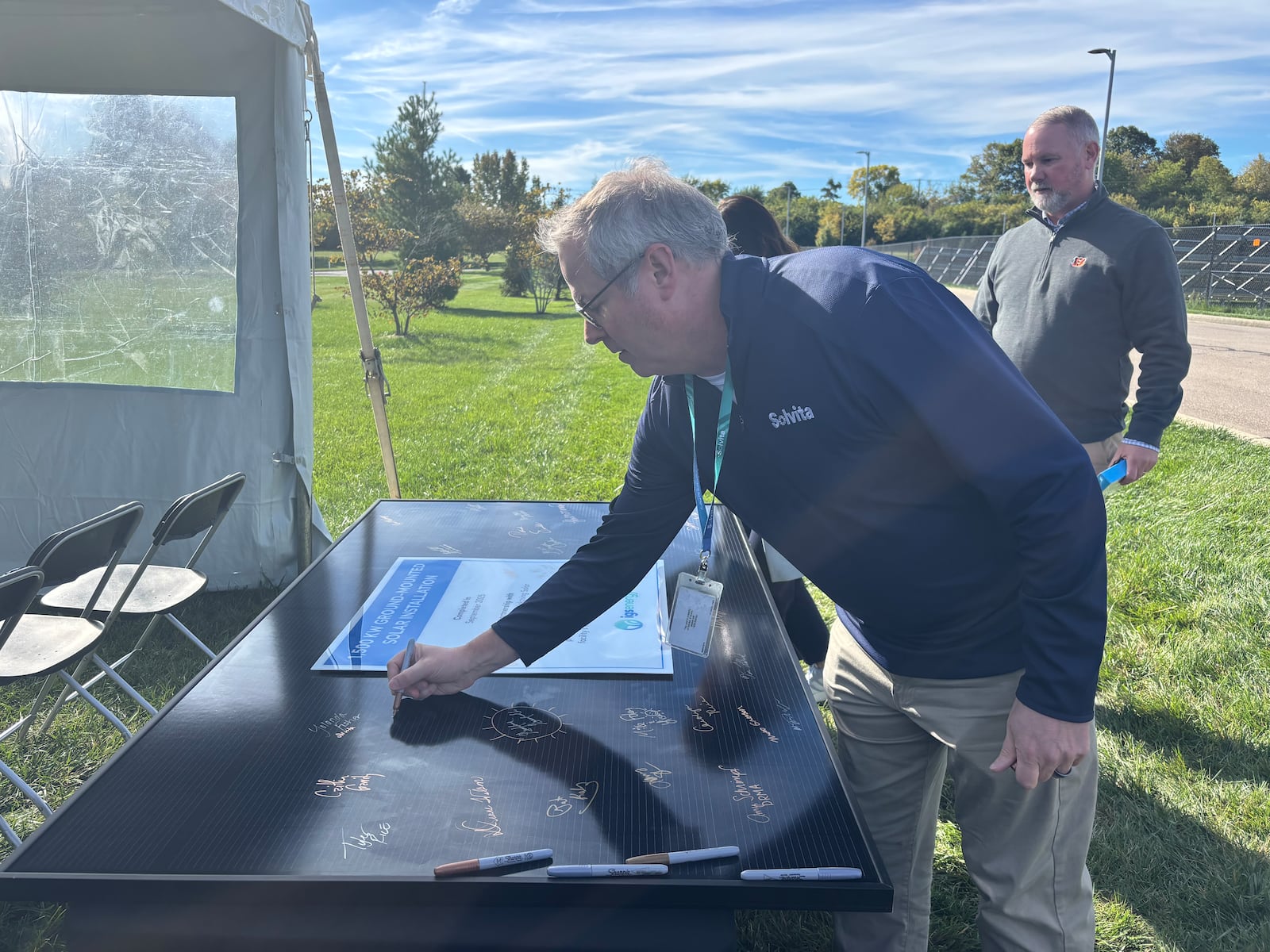 Chris Moore, vice president of human resources at Solvita in Kettering, signs a solar panel at the unveiling of Solvita's Solar Array on Friday, Oct. 17, 2025. CONTRIBUTED