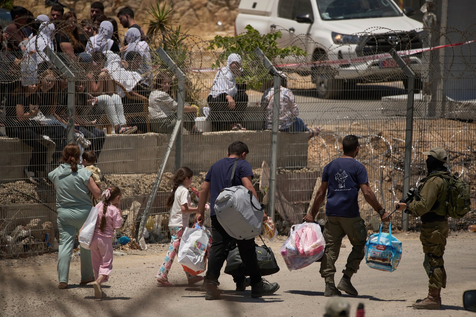 A Syrian Druze family cross back into Syria as they walk on the Israeli-Syrian border, at the Israeli-controlled Golan Heights town of Majdal Shams, Thursday, July 17, 2025. (AP Photo/Leo Correa)