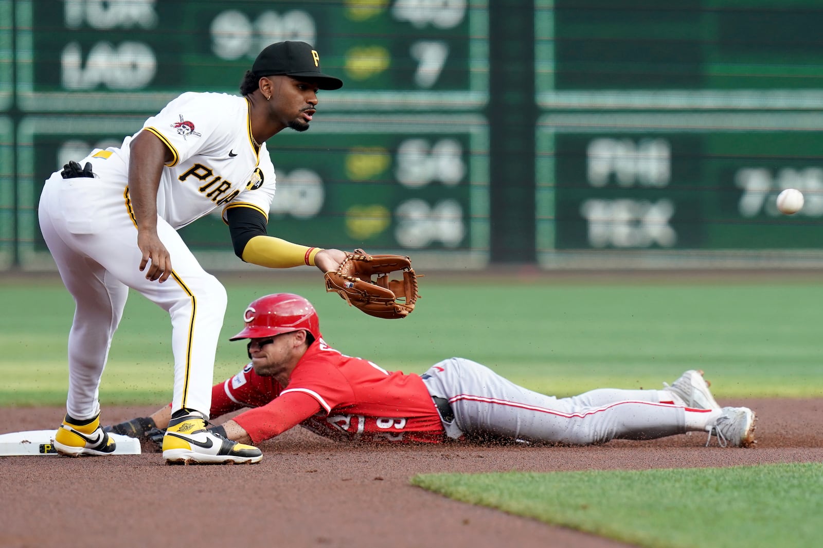 Cincinnati Reds' TJ Friedl, right, steals second base as Pittsburgh Pirates shortstop Liover Peguero, left, waits for a late throw during the first inning of a baseball game Saturday, Aug. 9, 2025, in Pittsburgh. (AP Photo/Matt Freed)