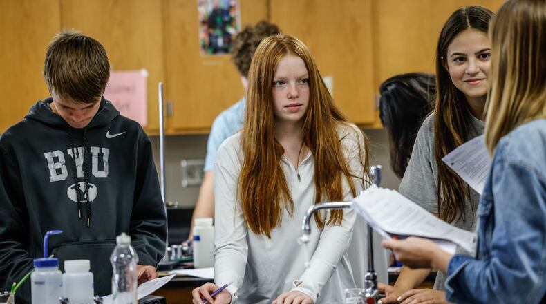 Springboro High School sophomores Clare Kofron (center) and Veronica Walli (right) talk with chemistry teacher Laura Houston (far right), during class Thursday September 15, 2022, as classmate Logan Carlisle works on an assignment. The Springboro school district scored five stars for achievement on state tests.  JIM NOELKER/STAFF
