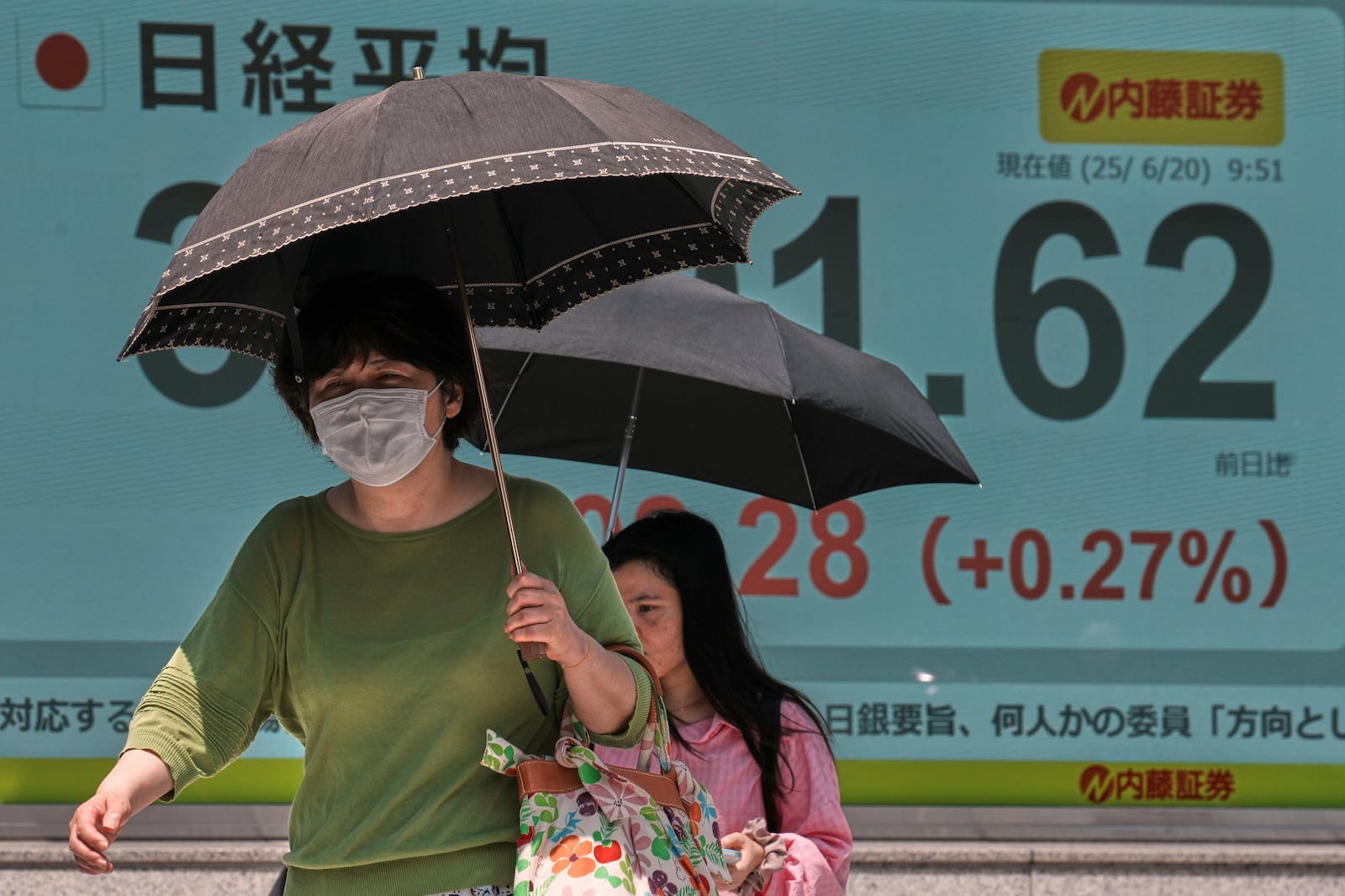 People walk in front of an electronic stock board showing Japan's Nikkei index at a securities firm Friday, June 20, 2025, in Tokyo. (AP Photo/Eugene Hoshiko)