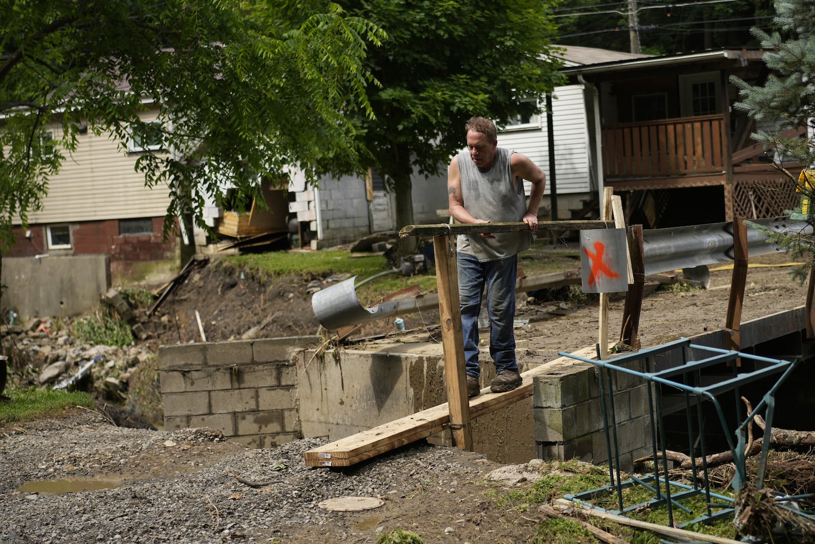 John Black puts up a board over a washed out foot bridge over Battle Run creek, Monday, June 16, 2025, in Valley Grove, W.Va. (AP Photo/Carolyn Kaster)