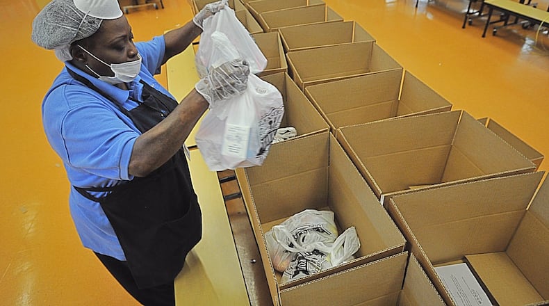 Brenda Nolan places food and milk in boxes at Dayton’s Westwood School to be given to students who would normally receive free lunch at school. MARSHALL GORBYSTAFF