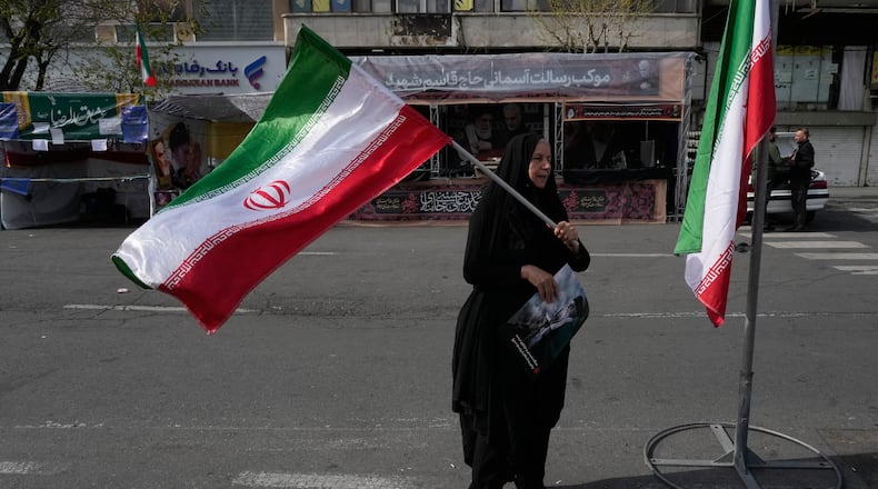 A woman waves an Iranian flag during a campaign in support of the government at the Enqelab-e-Eslami, or Islamic Revolution, square in downtown Tehran, Iran, Sunday, March 22, 2026. (AP Photo/Vahid Salemi)