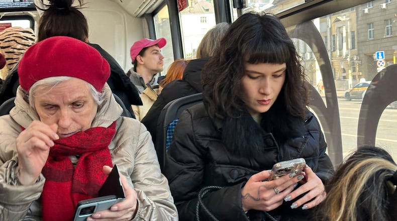 FILE - Women look at their smartphones while riding a bus in Moscow, on March 11, 2026. (AP Photo/Alexander Zemlianichenko, File)