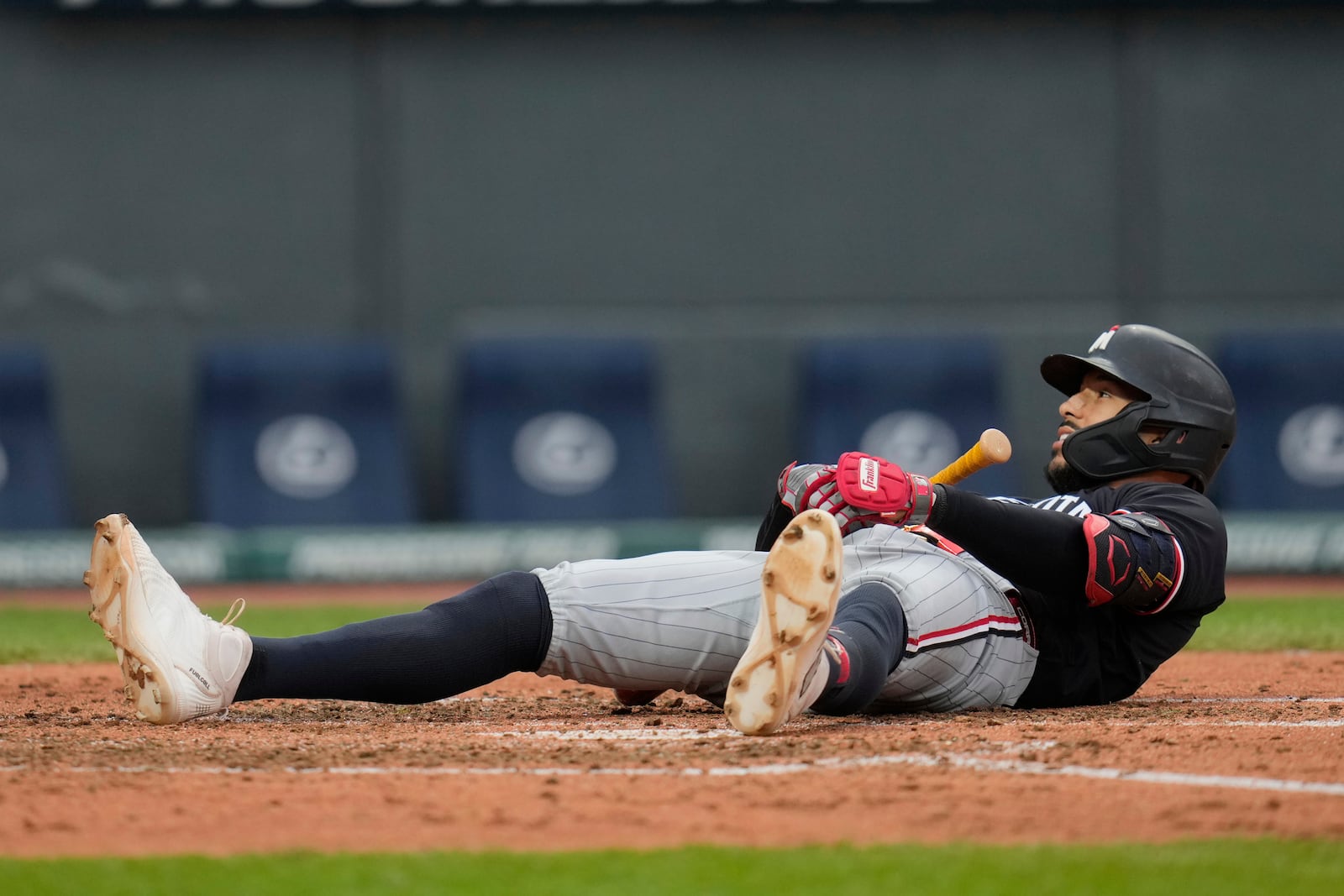 Minnesota Twins' Carlos Correa lies on the ground after falling over while backing away from a pitch in the sixth inning of a baseball game against the Cleveland Guardians in Cleveland, Wednesday, April 30, 2025. (AP Photo/Sue Ogrocki)
