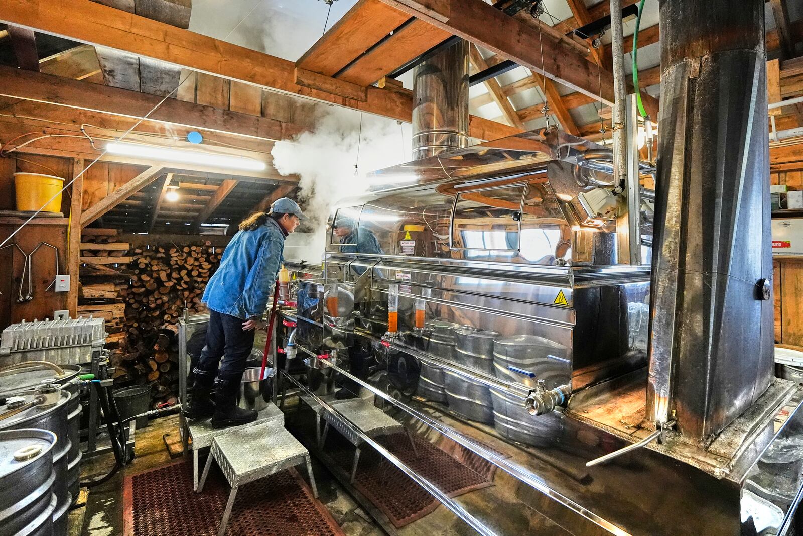 Donna Young checks the evaporator, one of the many pieces of Canadian-made equipment used for producing maple syrup at Judd's Wayeeses Farms in Morgan, Vt., on Friday, April 11, 2025. (AP Photo/Robert F. Bukaty)