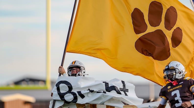 A Kenton Ridge High School football player carries their flag onto the field during their game against Northwestern earlier this season. CONTRIBUTED PHOTO BY MICHAEL COOPER
