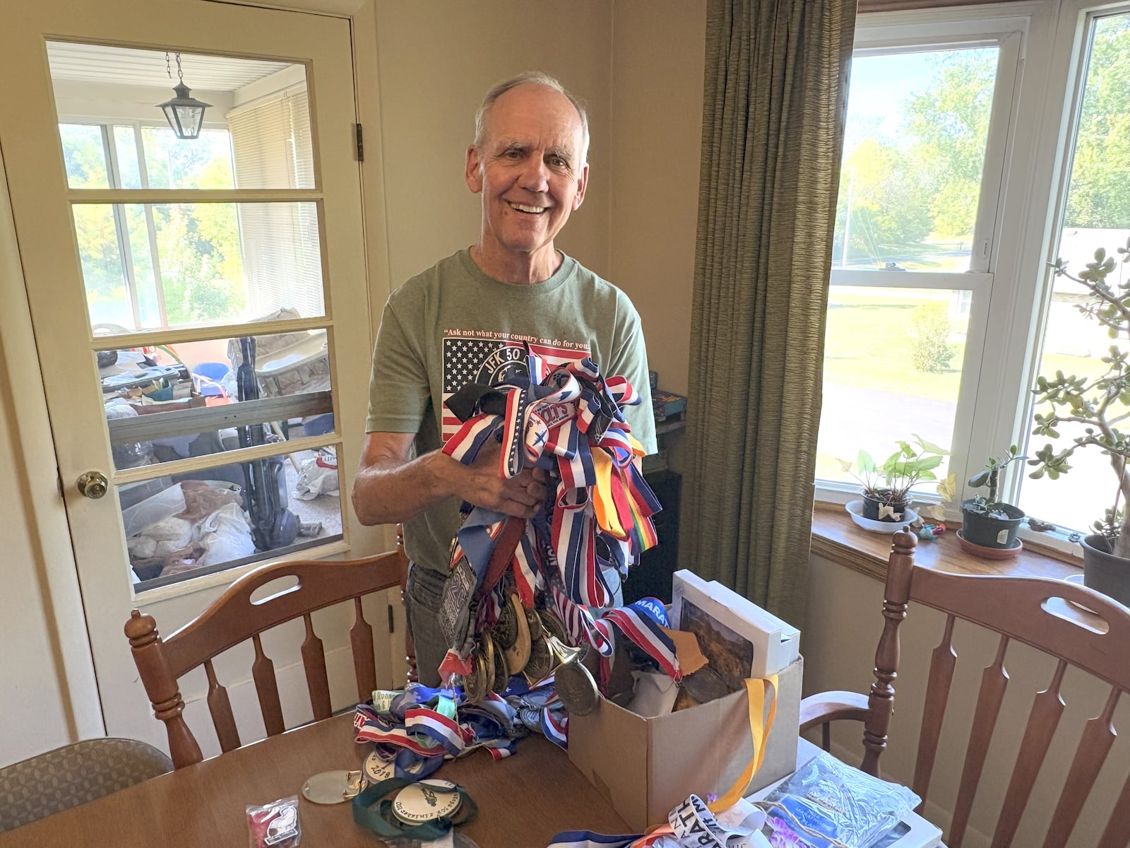 At his Vandalia home, Stars runner Steve Wirick holds a handful of the medals he’s won in a running career that includes 111 ultra marathons and 55 marathons, including every U.S. Air Force Marathon since the race began in 1997. TOM ARCHDEACON/CONTRIBUTED PHOTO