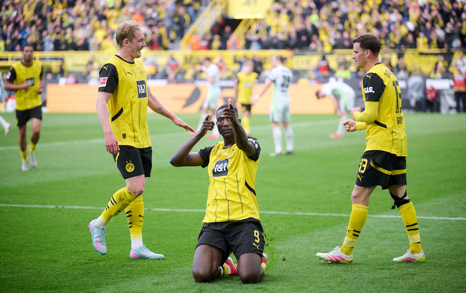Dortmund's Serhou Guirassy, center, celebrates his goal with Julian Brandt, left and Pascal Groß, during the German Bundesliga soccer match between Borussia Dortmund and VfL Wolfsburg, at Signal Iduna Park, in Dortmund, Germany, Saturday, May 3, 2025. (Bernd Thissen/dpa via AP)