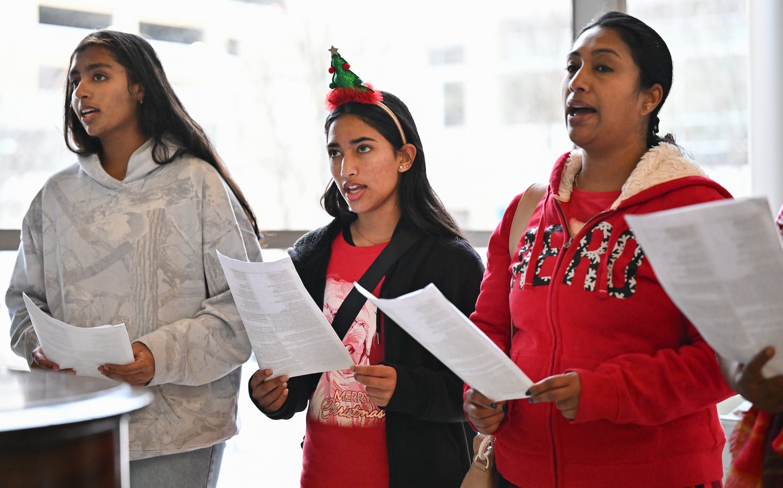 From left to right, Nissi Xavier, Annette Thomas and Mevitha Natthew sing carols on Monday, Dec. 22 at Miami Valley Hospital in Dayton with a group organized by Scott Davidson. The group also sang at Miami Valley Hospital North and South on Monday. BRYANT BILLING/STAFF