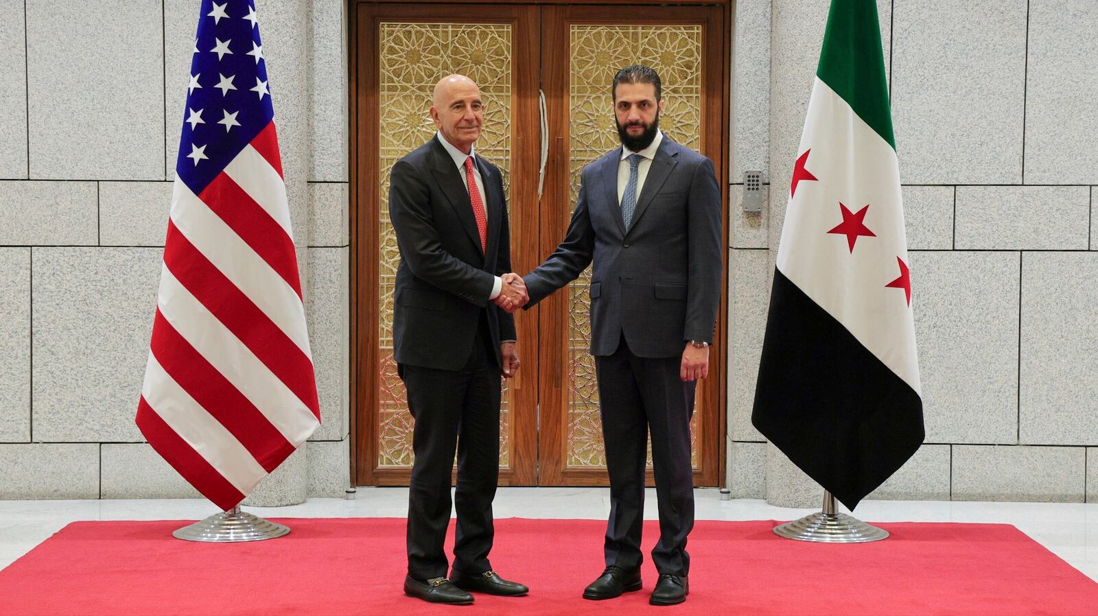 In this photo released by the Syrian official news agency SANA, Syria's interim President Ahmad al-Sharaa, right, shakes hands with U.S. Ambassador to Turkey and Special Envoy to Syria Tom Barrack, in Damascus, Syria, May 29, 2025. (SANA via AP)