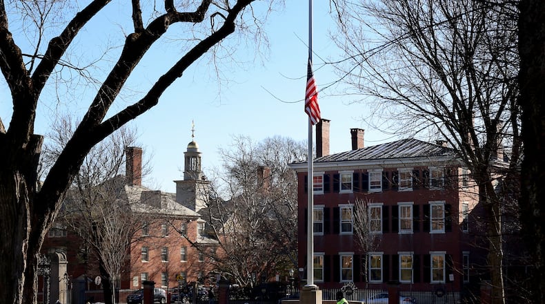 A security guard walks past a flag at half-staff on the main green of Brown University in Providence, RI, Thursday, Dec. 18, 2025, (AP Photo/ Mark Stockwell)