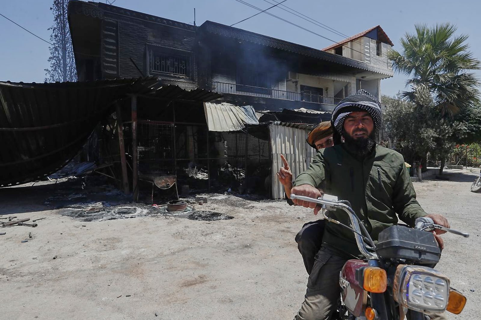Syrian government soldiers drive in front of a house that was burned during the clashes between the Syrian government forces and Druze militias on the outskirts of Sweida city, southern Syria, Wednesday, July 16, 2025. (AP Photo/Omar Sanadiki)