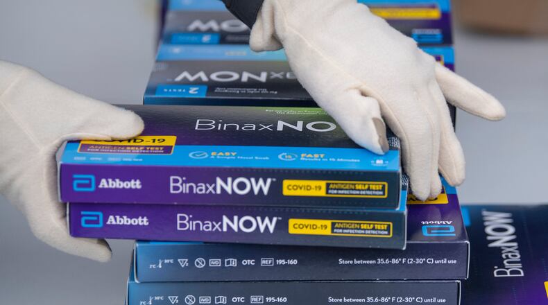 FILE - Youngstown City Health Department worker Faith Terreri grabs two at-home COVID-19 test kits to be handed out during a distribution event, Dec. 30, 2021, in Youngstown, Ohio. Starting Saturday, private health insurers will be required to cover up to eight home COVID-19 tests per month for those on their plans, the Biden administration announced Monday, as it looks to lower costs and make testing for the virus more convenient amid rising frustrations. (AP Photo/David Dermer, File)