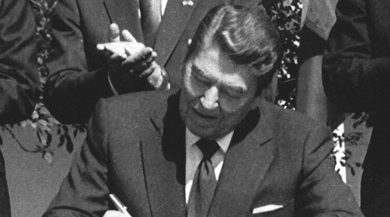 FILE - President Ronald Reagan signs legislation implementing the U.S.-Canada free trade agreement during a ceremony at the White House, Sept. 28, 1988. (AP Photo/Scott Stewart, File)