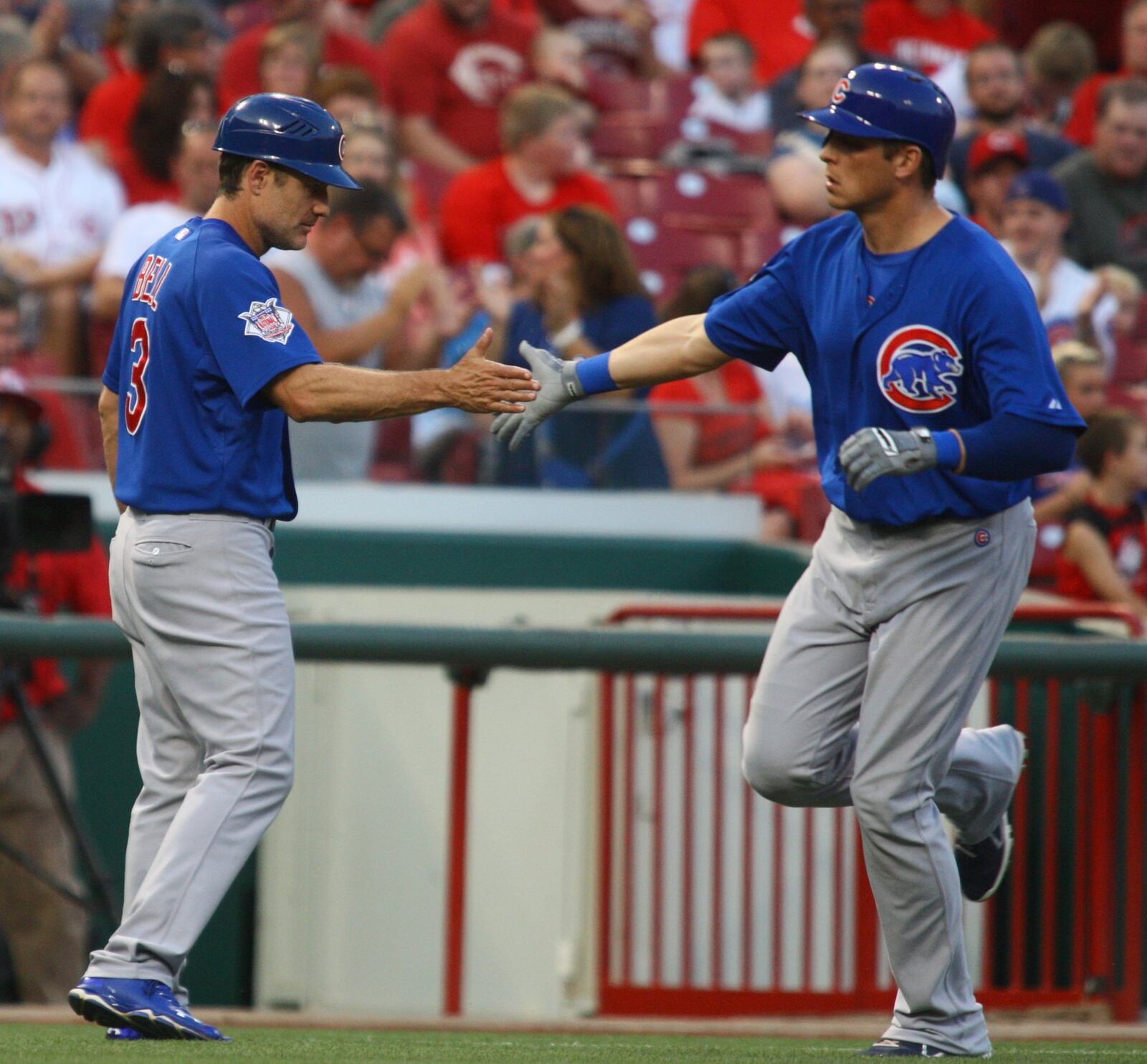 The Cubs’ Ryan Sweeney slaps hands with third-base coach David Bell after a home run against the Reds on Monday, Sept. 9, 2013, at Great American Ball Park in Cincinnati. David Jablonski/Staff