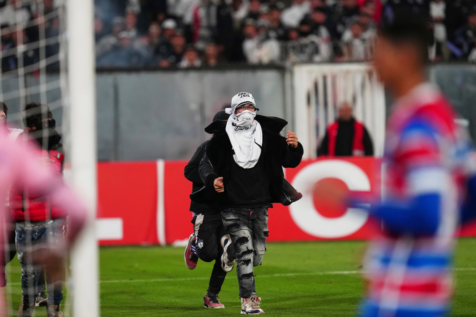 Fans invade the field during a Copa Libertadores Group E soccer match between Chile's Colo Colo and Brazil's Fortaleza at the Monumental stadium in Santiago, Chile, Thursday, April 10, 2025. (AP Photo/Esteban Felix)