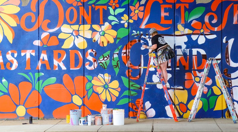 Tiffany Clark repainting parts of her "Don't Let The Bastards Grind You Down" mural after it was vandalized on Sunday. DION JOHNSON / STAFF
