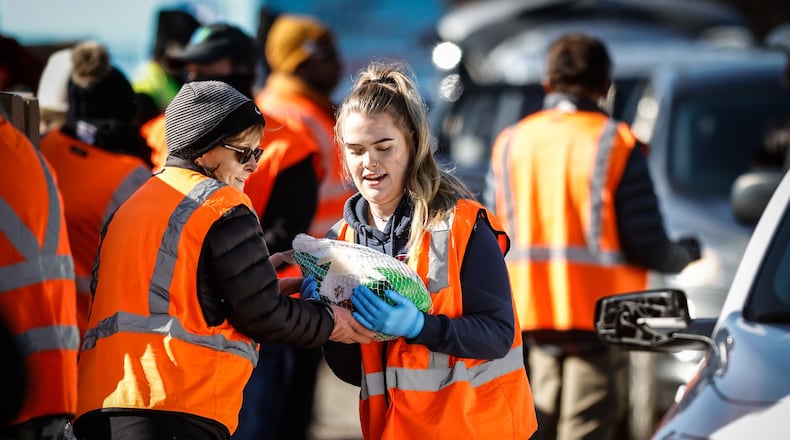 Karen Morris, left, hands a turkey to her daughter, Shea Morris to load into a vehicle at the Thanksgiving distribution supported by the Food Bank and the Levin Family Foundation held at the Dixie Drive Inn Tuesday afternoon Nov. 23, 2021. JIM NOELKER/STAFF