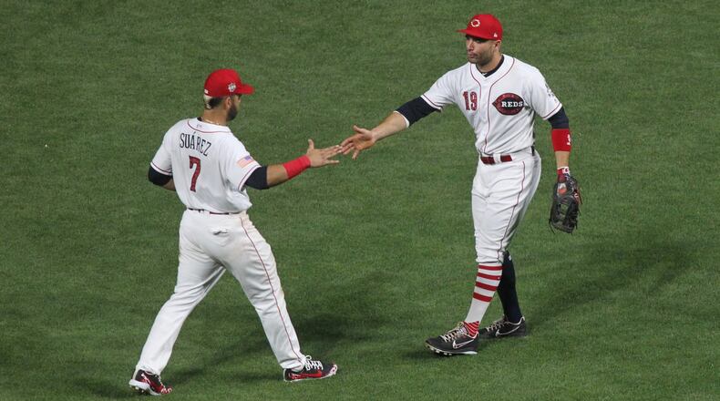 The Reds’ Eugenio Suarez and Joey Votto celebrate after a victory against the White Sox on Monday, July 2, 2018, at Great American Ball Park in Cincinnati. David Jablonski/Staff