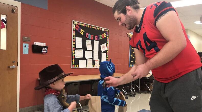 RYAN 8 – Former Dayton Flyers offensive lineman Ryan Culhane gives some candy to a young Trick-or-Treater during Halloween celebrations at Horace Mann Elementary in 2018 . CONTRIBUTED