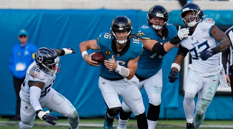 Jacksonville Jaguars quarterback Trevor Lawrence (16) runs the ball past Tennessee Titans outside linebackers Truman Jones (56) and Jaylen Harrell, far right, during the second half of an NFL football game Sunday, Jan. 4, 2026, in Jacksonville, Fla. (AP Photo/John Raoux)