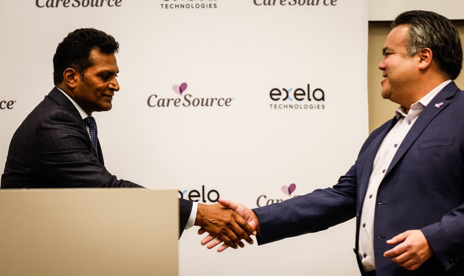 Exela President Suresh Yannamani, left and CareSource President & CEO, Erhardt Preitauer shake hands at a press conference Thursday, Oct. 28, 2021, announcing Exela will bring about 100 jobs to Dayton. Jim Noelker/Staff