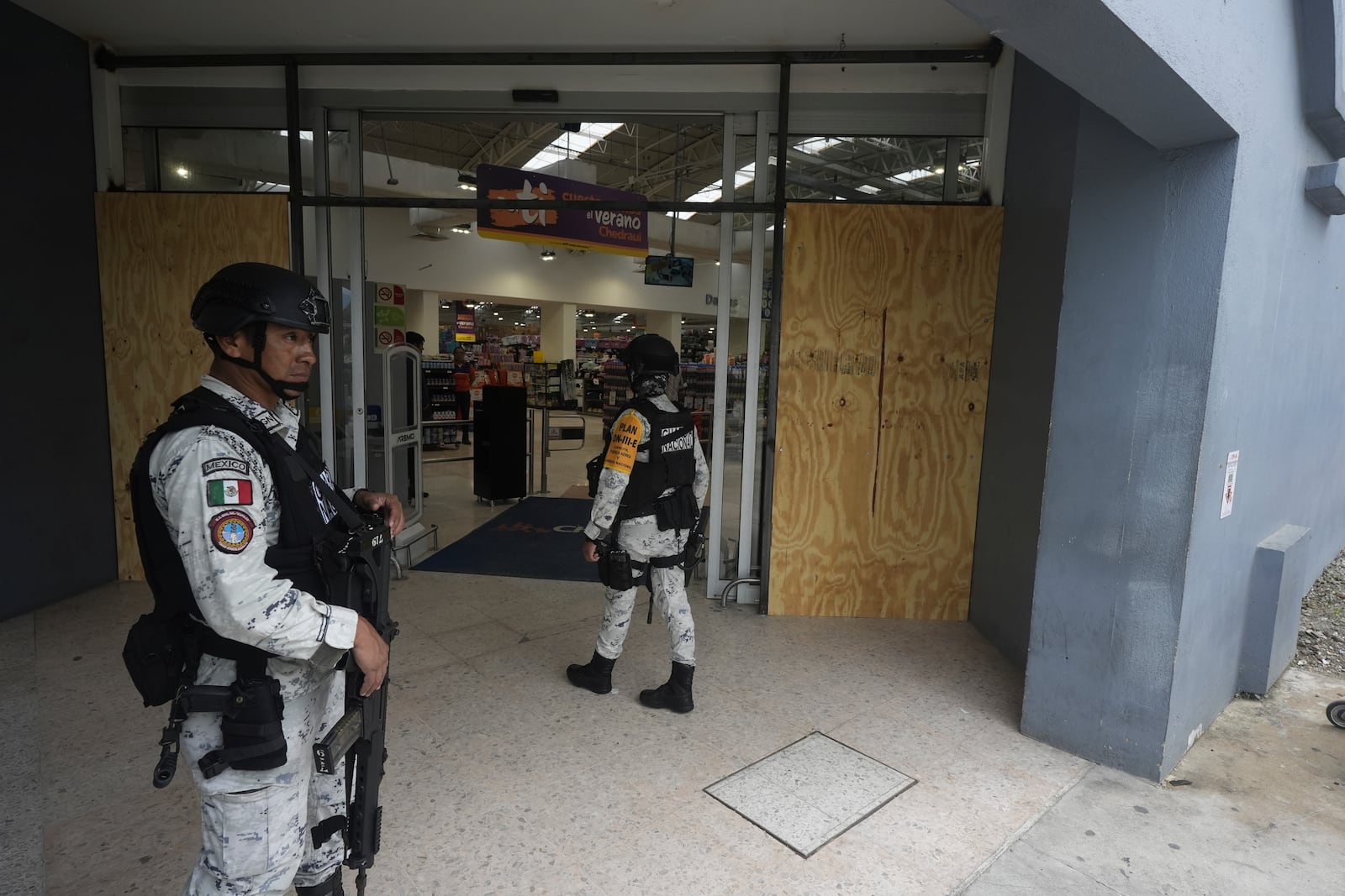 National Guards stand guard at the entrance to a grocery store on Manzanillo beach after Hurricane Erick hit near Acapulco, Mexico, Thursday, June 19, 2025. (AP Photo/Fernando Llano)