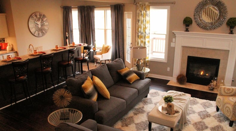 A wall was removed to open up the kitchen, and now an island with tiered bar seating doubles as a separation from the great room where tall windows flank the fireplace with its substantial white mantel and fluted posts.