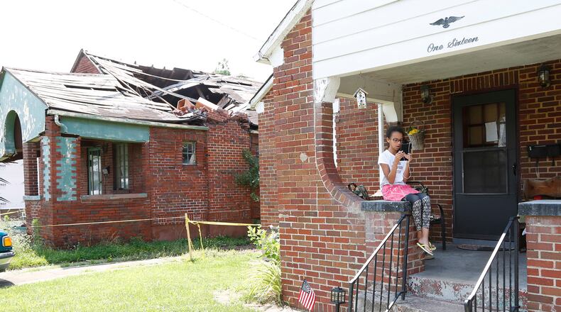 Madison Thompson, 10, sings along to a song learning app on her porch in Old North Dayton which had dozens of homes destroyed after the Memorial Day tornado. Her family's home was not damaged as badly as their neighbors.  TY GREENLEES / STAFF