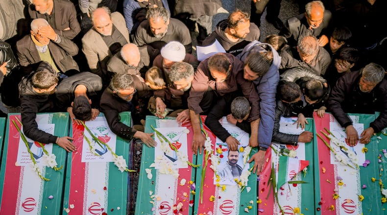 Mourners reach out to coffins during a funeral for people killed during the ongoing U.S.–Israeli military campaign in Qom, Iran, Thursday, March 5, 2026. (Seyyed Mehdi Alavi/ISNA via AP)