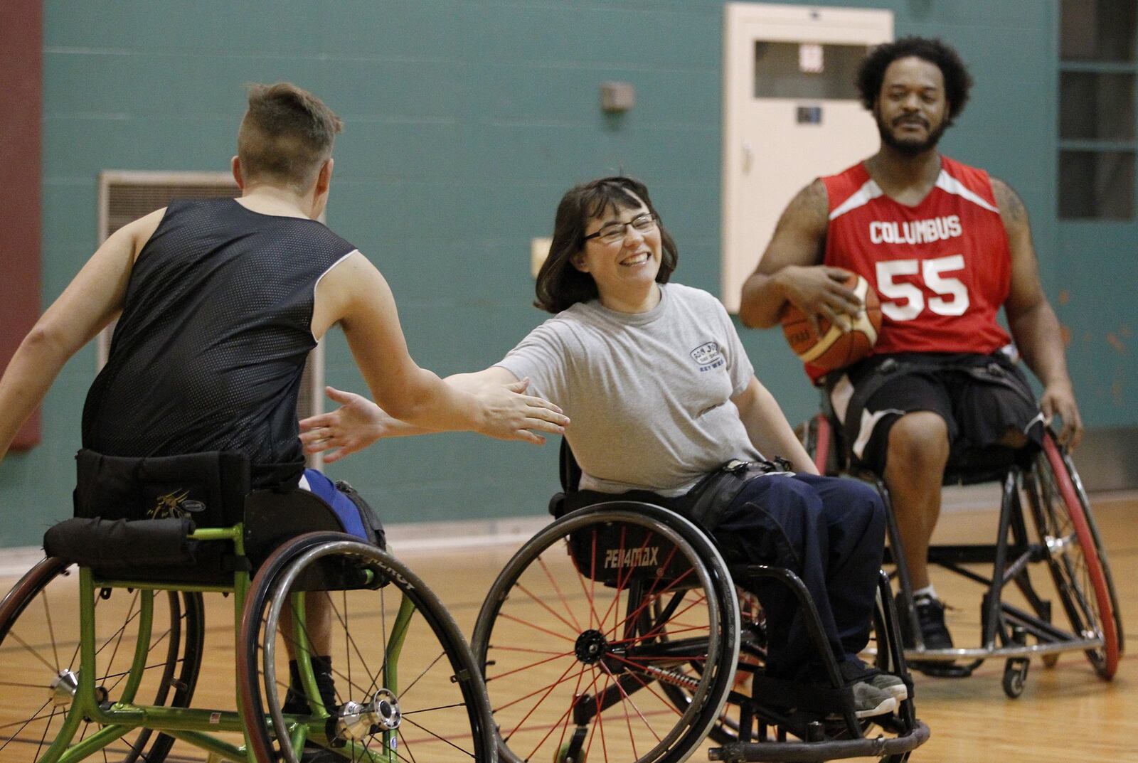 Lindsey McGlinch of Arcanum and teammates on the Miami Valley Raptors wheelchair basketball team encourage each other during a recent practice. LISA POWELL / STAFF