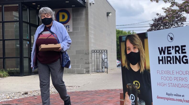 A customer of Dewey's Pizza in Dayton walks by a "We're Hiring" sign. The Dayton region added 1,200 jobs last month. CORNELIUS FROLIK / STAFF