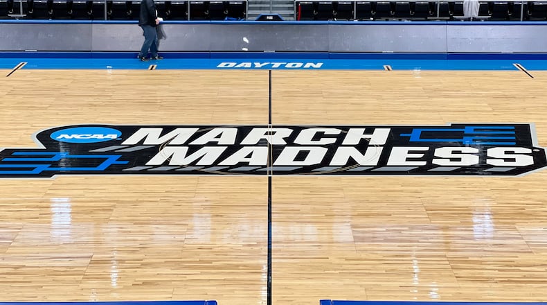 Workers on Sunday put the finishing touches on the basketball court installation for the First Four of the NCAA Division I Men’s Basketball Championship at UD Arena. AIMEE HANCOCK/STAFF